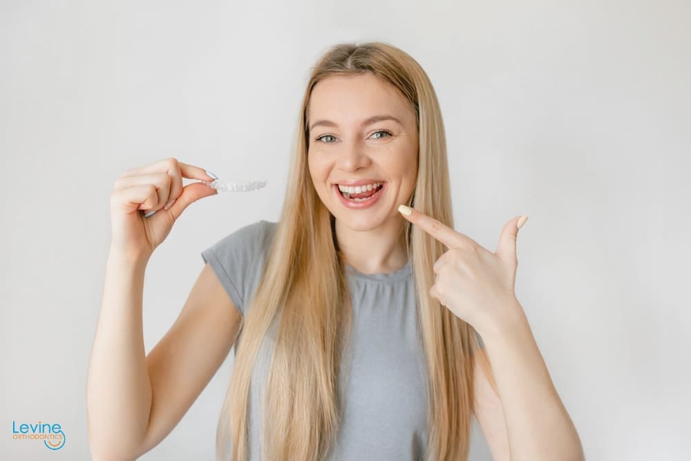 A woman wearing a striped shirt smiling brightly, showing off her well-aligned teeth after orthodontic care by orthodontist in Fort Myers, FL.
