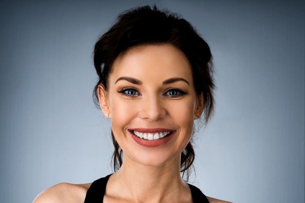 a woman with clear braces from orthodontist in Fort Myers and Cape Coral, FL smiling at the camera 